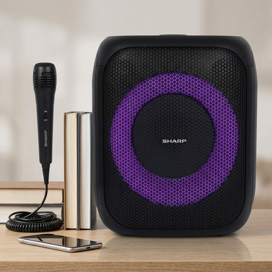 Sharp PS-914 party speaker with mic and stacked books on a wooden desk.