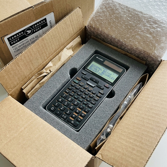 An aerial view shows the Sharp scientific calculator nested safely and securely within customized foam inserts and a standard corrugated cardboard shipping box, half-opened to reveal protective padding.