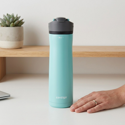 A 24oz Contigo water bottle stands upright beside a human hand on a clean wooden desk surface for size comparison.